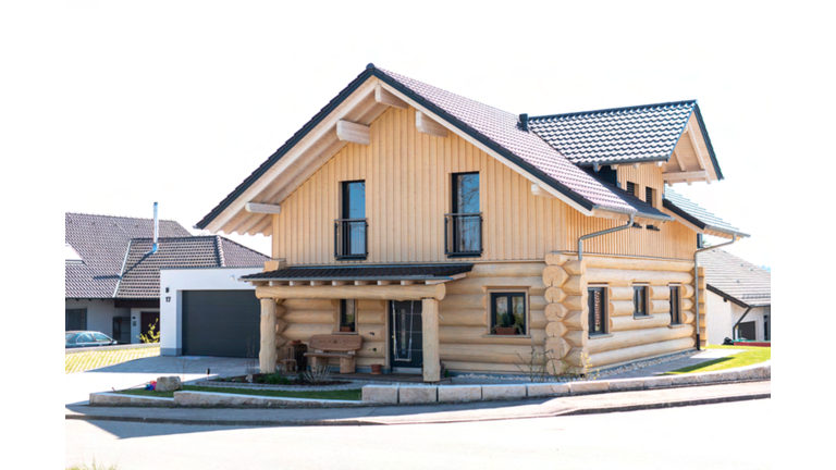 Blockhaus mit Garage und Vordach, von vorne fotografiert, helles Holz